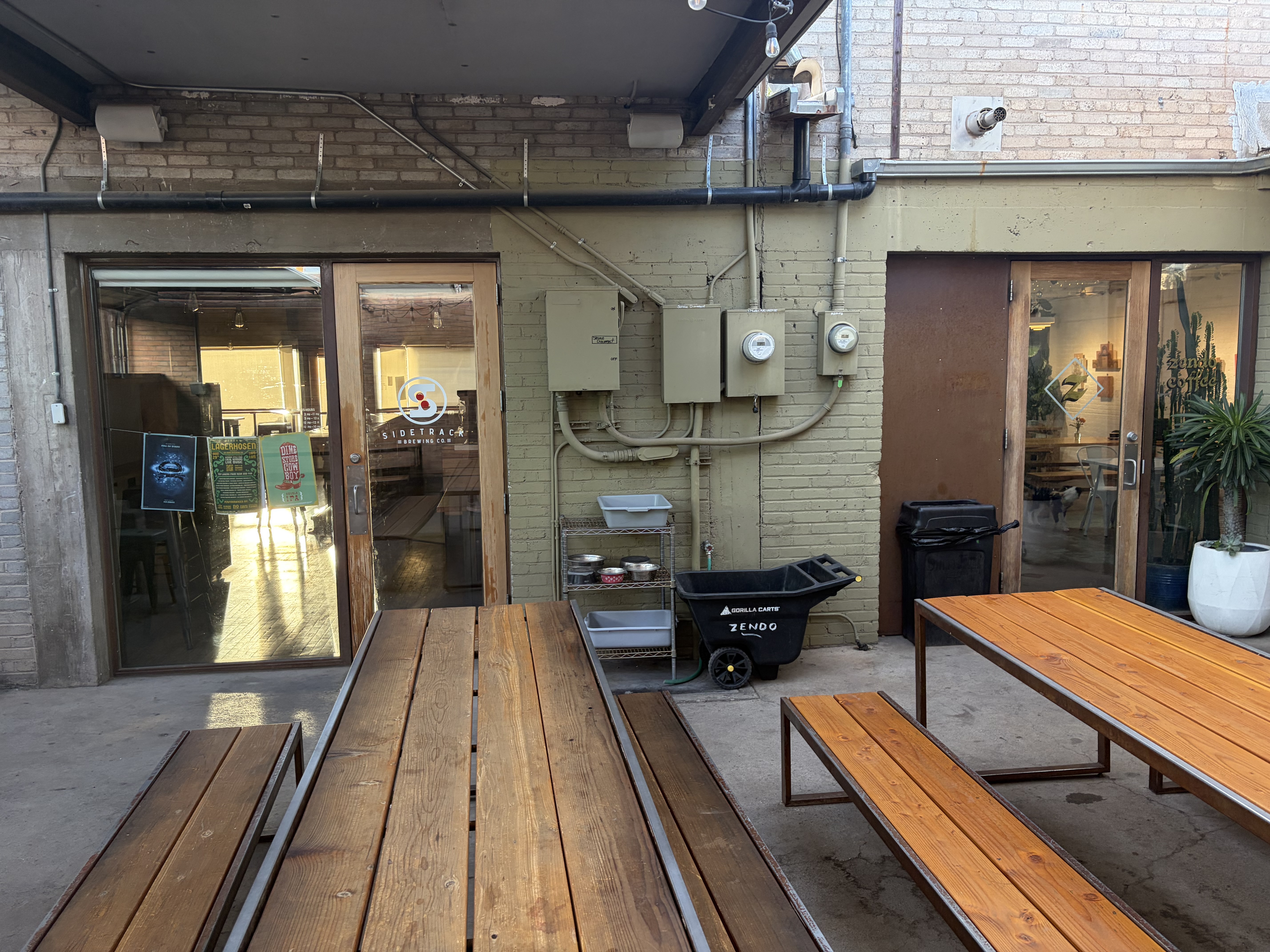 A shared courtyard between two businesses: the Sidetrack Brewing door on the left, the Zendo door on the right, with a cart lettered ZENDO between them.